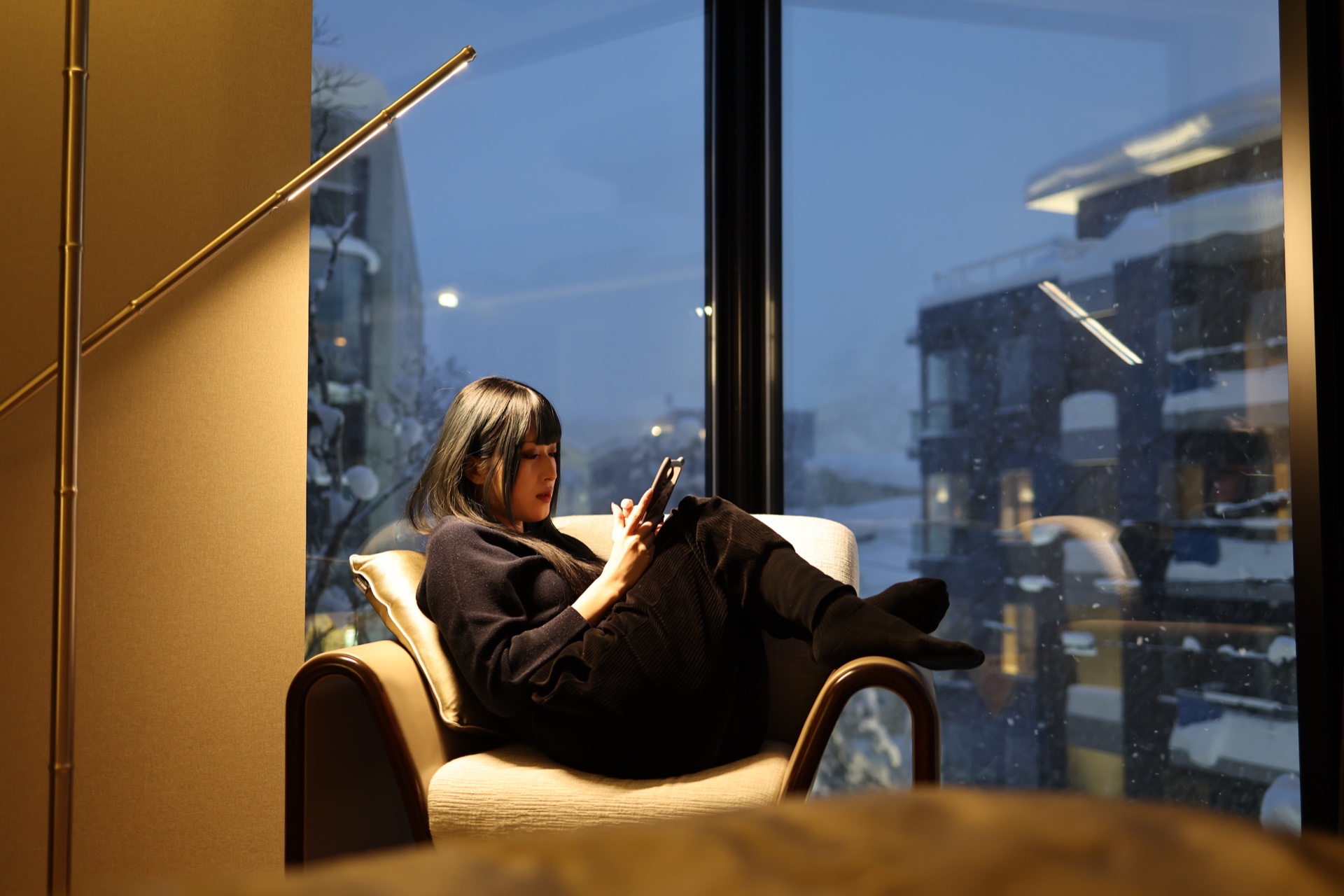 Guest relaxing by the window at dusk with Niseko snow view
